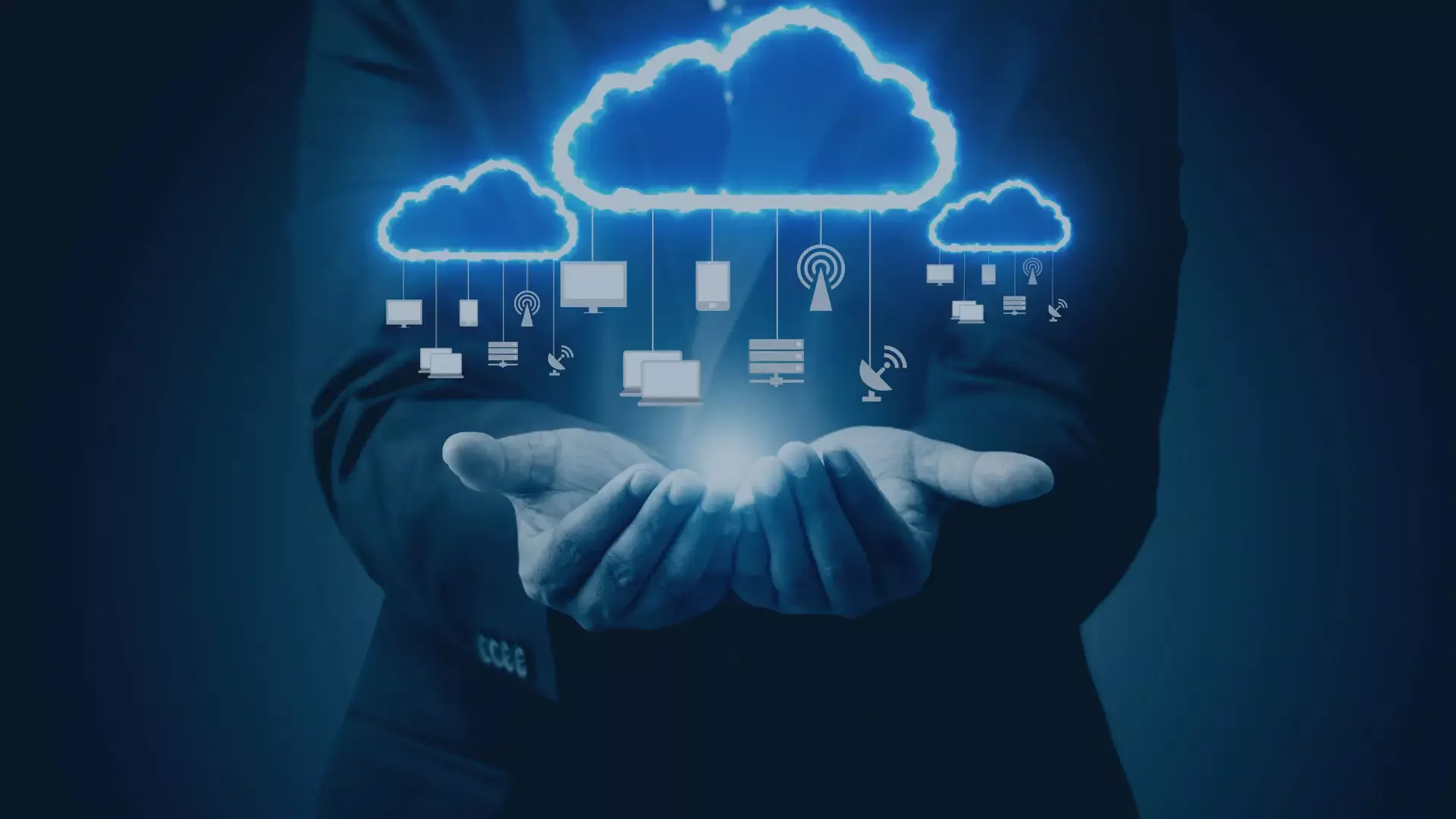 Businessperson hält digitale Cloud-Symbole über den Händen, verbunden mit Geräten und Servern – Darstellung von Cloud-Computing und vernetzter IT-Infrastruktur.