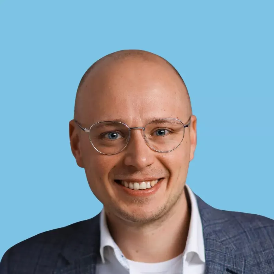 Porträt eines lächelnden Mannes mit Brille vor blauem Hintergrund als Kundenstimme, symbolisiert positive Erfahrungen und Testimonials.